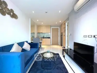 Modern open-plan living space with sleek blue sofa set, integrated kitchen, and contemporary finishes, perfect for urban living.