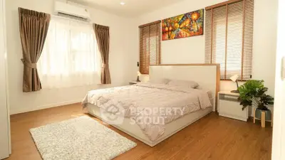 Spacious bedroom with modern decor and natural light, featuring wooden floors and stylish window treatments.