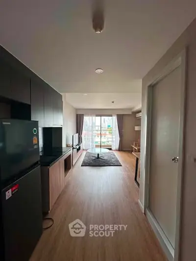 Modern apartment interior with open layout, featuring sleek kitchen and spacious living area with balcony view.