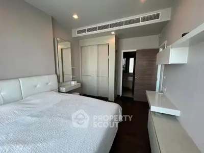 Modern bedroom with sleek design, featuring a cozy bed, built-in wardrobe, and stylish shelving.