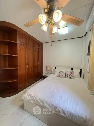 Cozy bedroom with wooden built-in wardrobe and ceiling fan