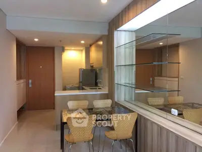 Modern kitchen and dining area with wooden accents and glass shelving in a cozy apartment.