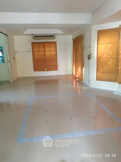 Spacious empty room with tiled flooring and large windows, perfect for customization.