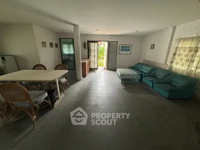 Spacious living room with cozy seating and dining area, featuring natural light and garden access.