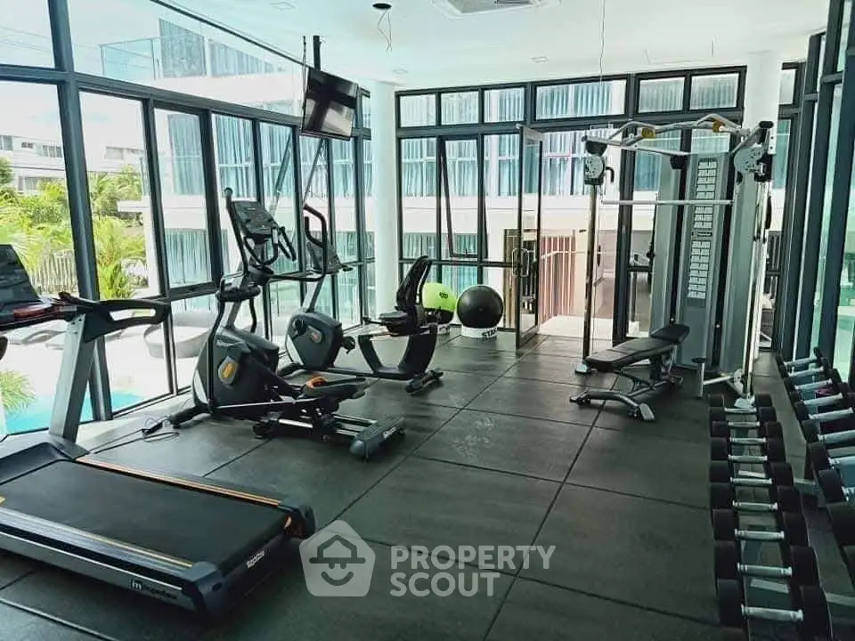Modern gym with state-of-the-art equipment and pool view in luxury residential complex.