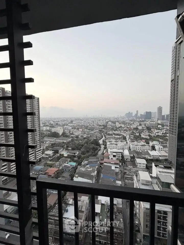 Stunning cityscape view from high-rise balcony with urban skyline and sunset hues.