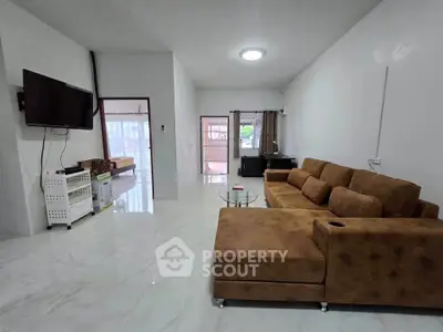 Spacious living room with modern brown sofa and wall-mounted TV in a bright, airy home.