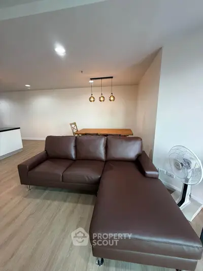Spacious living room with modern brown leather sofa and stylish lighting