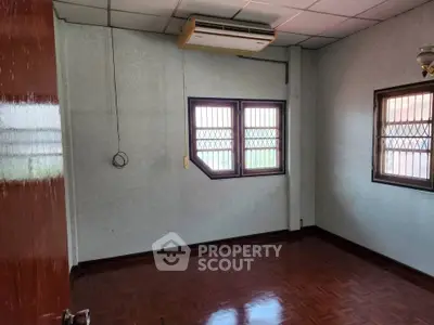 Spacious empty room with wooden flooring and air conditioning, ideal for customization.