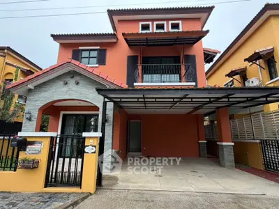 Charming two-story house with vibrant orange facade and spacious carport in a suburban neighborhood.