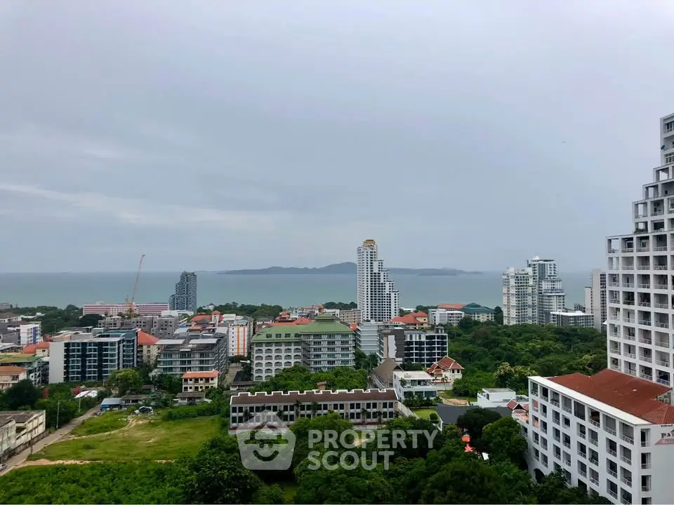 Stunning cityscape view with ocean backdrop, showcasing modern high-rise buildings and lush greenery.