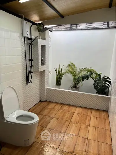 Modern bathroom with wooden flooring and indoor plants, featuring a sleek toilet and shower area.