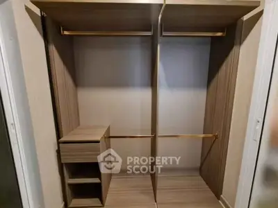 Spacious walk-in closet with wooden shelves and hanging rods, perfect for organized storage.