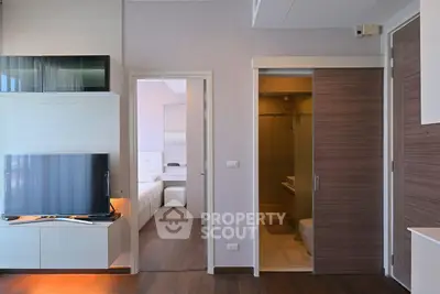 Modern apartment interior with sleek living room and adjacent bedroom, featuring stylish wooden flooring and contemporary design.