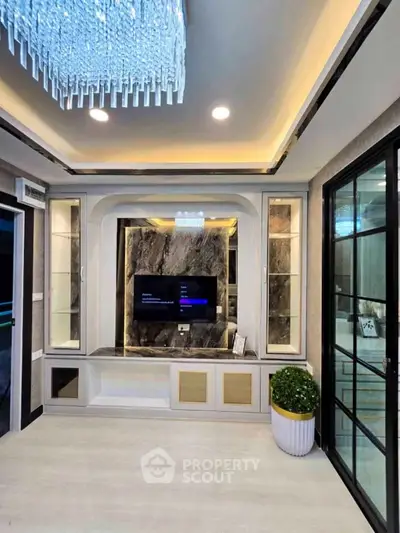 Luxurious living room with modern chandelier and elegant built-in TV unit.