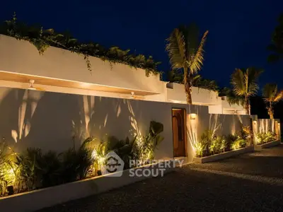 Stunning modern villa exterior with lush landscaping and ambient lighting at night.
