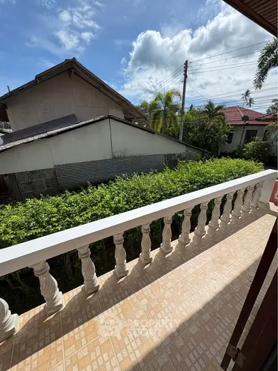 Charming balcony with lush greenery and scenic neighborhood view, perfect for relaxation.