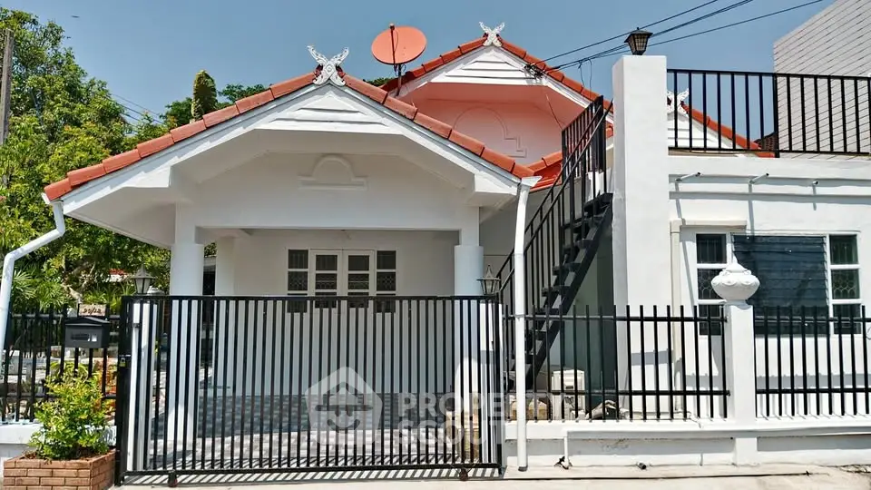 Charming single-story house with red-tiled roof and gated entrance, ideal for family living.