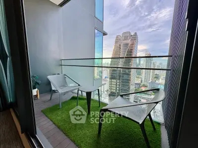 Modern balcony with city view, featuring stylish chairs and artificial grass flooring.