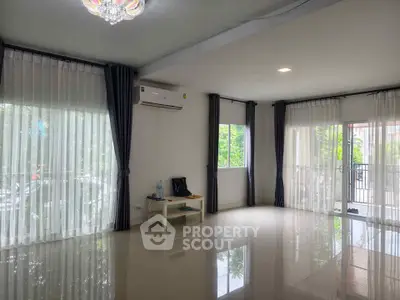 Spacious living room with large windows and modern decor, perfect for natural light and comfort.