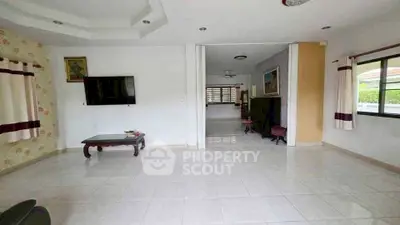 Spacious living room with tiled flooring and large windows for natural light.