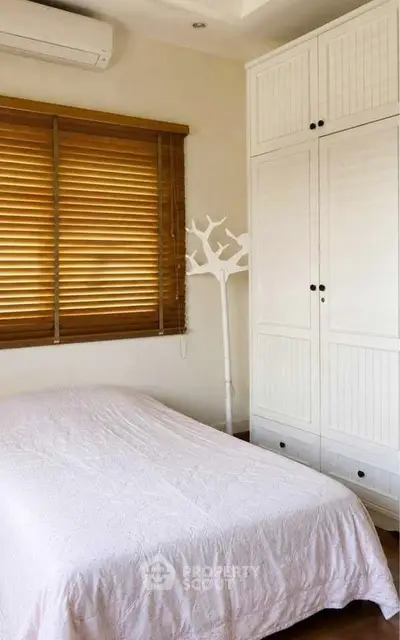Cozy bedroom with white wardrobe and wooden blinds, perfect for a serene retreat.