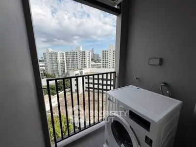 High-rise apartment balcony with washing machine and city skyline view.