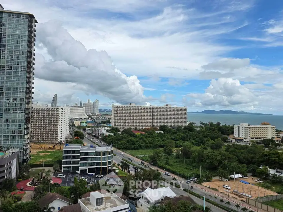 Stunning high-rise view of coastal cityscape with lush greenery and ocean backdrop.