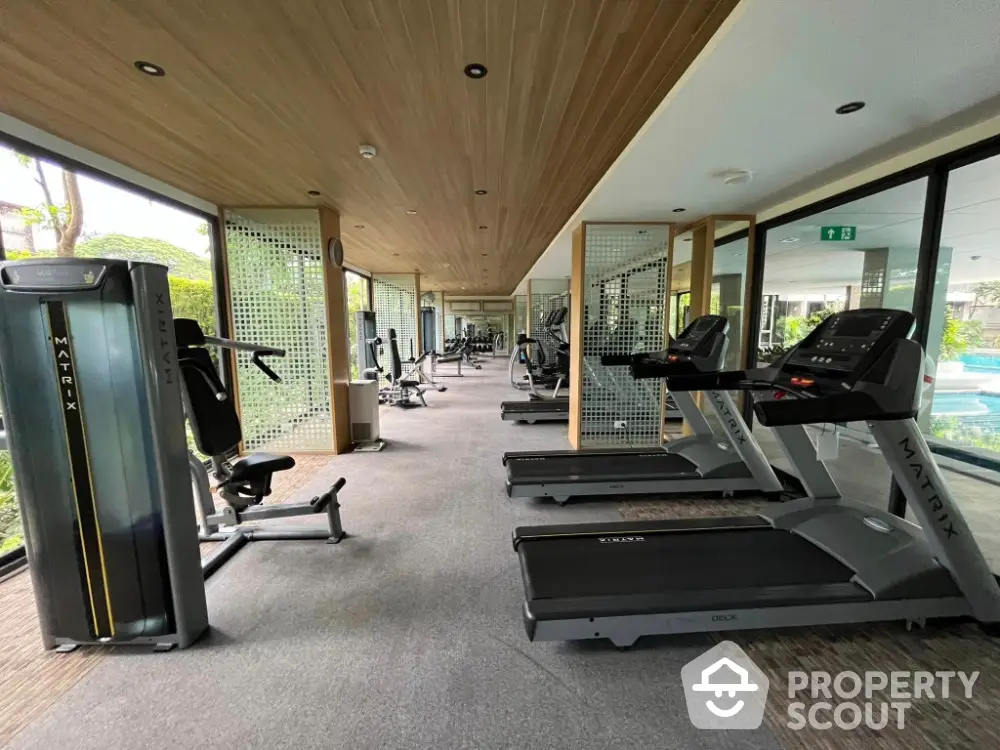 Modern gym with state-of-the-art equipment and large windows overlooking greenery.