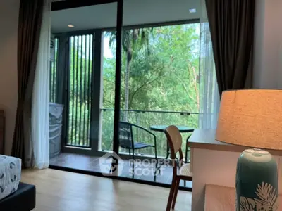 Charming living room with balcony view of lush greenery, perfect for relaxation and nature lovers.