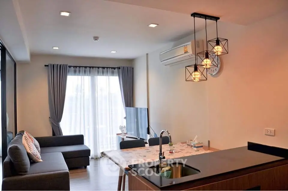 Modern living room with stylish lighting and open kitchen layout in a cozy apartment.