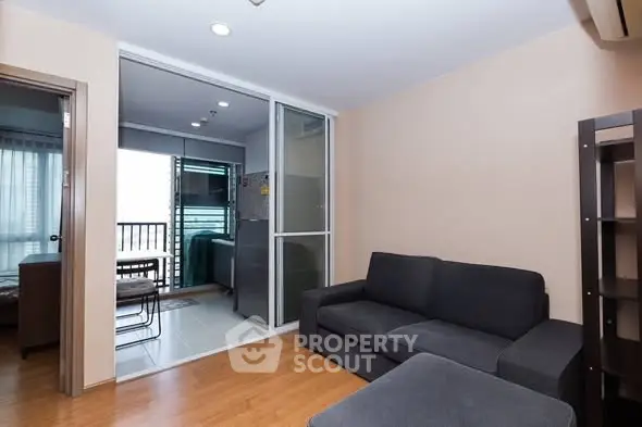 Modern living room with cozy sofa and sliding glass doors leading to a balcony.