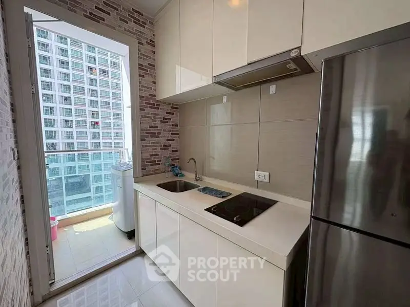 Modern kitchen with sleek cabinetry and balcony view in high-rise apartment