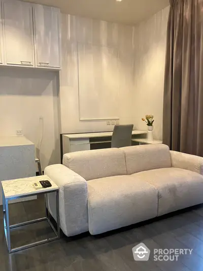 Elegant modern living space with a plush sofa and sleek dining area, complemented by soft neutral tones and tasteful decor, perfect for urban living.