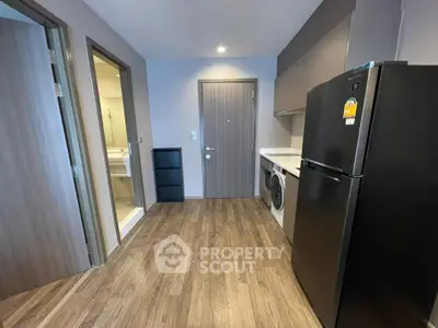 Modern apartment entryway with sleek kitchen appliances and wood flooring