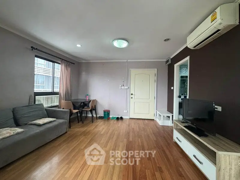 Spacious living room with modern decor and natural light, featuring wooden flooring and a cozy seating area.
