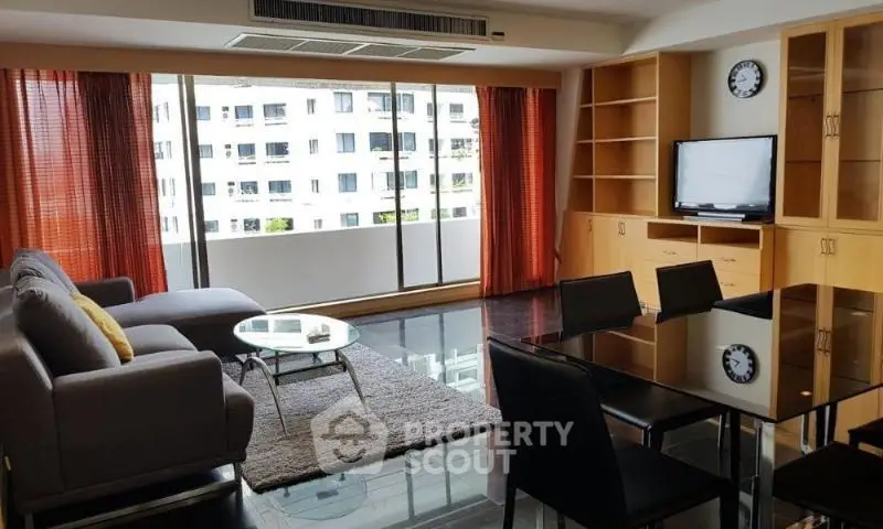 Spacious living room with modern furniture and large windows offering a city view.