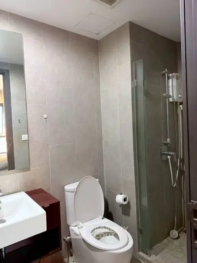 Modern bathroom with sleek fixtures and neutral tiles, featuring a glass shower enclosure.