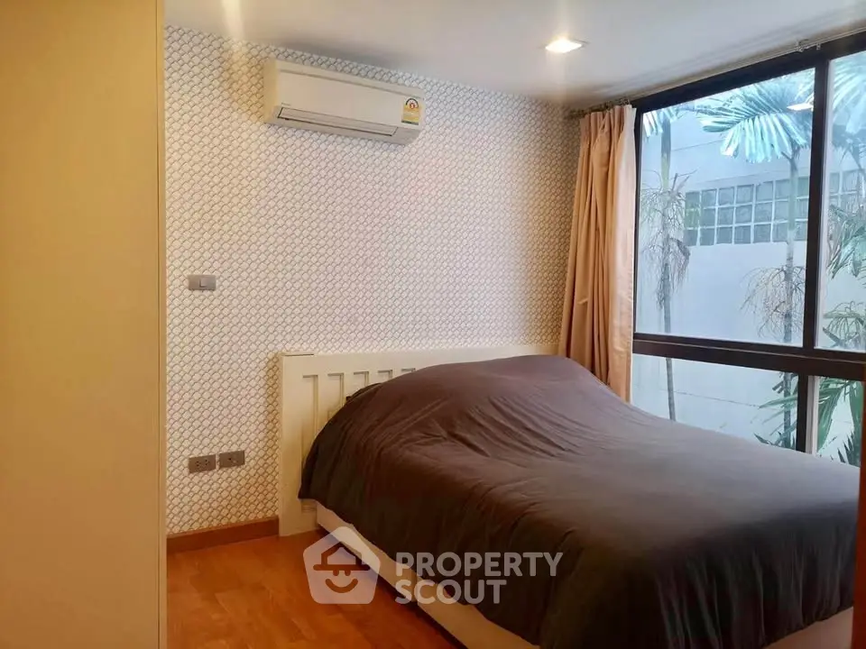 Cozy bedroom with large window and air conditioning in modern apartment