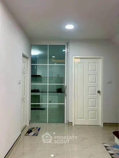 Modern interior with sleek glass door and tiled flooring, showcasing a minimalist design.
