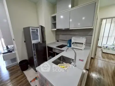 Modern kitchen with sleek cabinetry and stainless steel appliances in a cozy apartment setting.