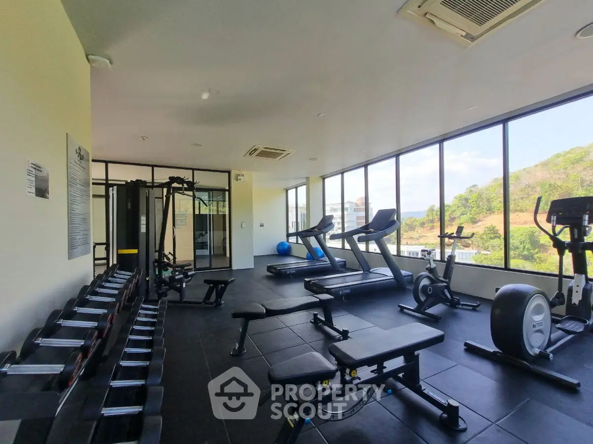 Spacious modern gym with panoramic windows and state-of-the-art equipment in a luxury property.