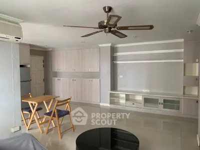 Spacious living room with modern ceiling fan and built-in storage cabinets, perfect for comfortable living.