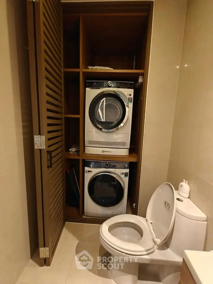 Compact bathroom with integrated washer and dryer in sleek wooden cabinet.