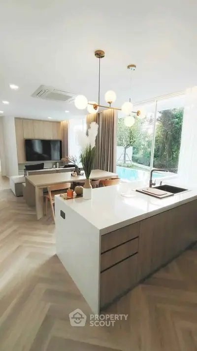 Modern open-plan living room with kitchen island and pool view