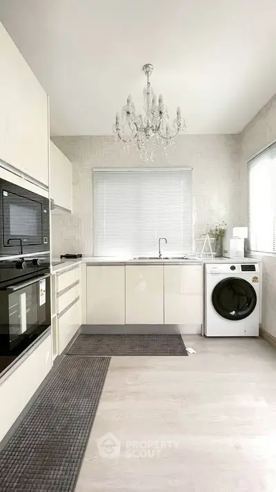Modern kitchen with chandelier, built-in oven, and washing machine