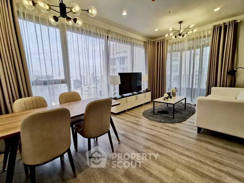 Spacious modern living room with large windows and elegant decor in a high-rise apartment.