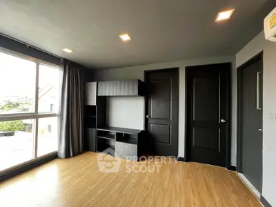 Spacious modern living room with large window and wooden flooring