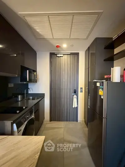 Modern kitchen with sleek appliances and closed layout, featuring washing machine and fridge.