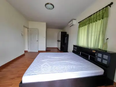 Spacious bedroom with wooden flooring and large window for natural light